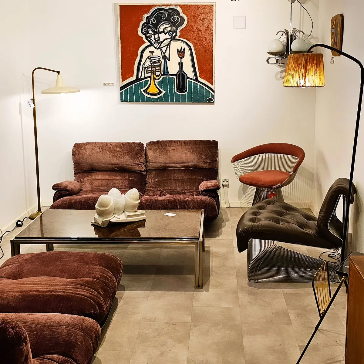 Intérieur de showroom présentation d'un canapé marron, d'une table basse, de luminaires et d'un tableau.