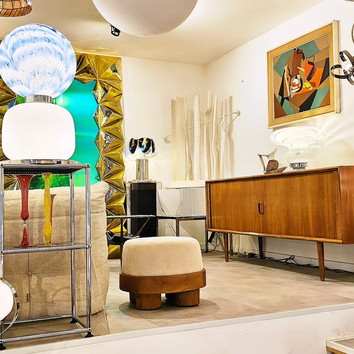 Showroom de mobilier vintage avec luminaires design, un buffet en bois et une œuvre d'art.