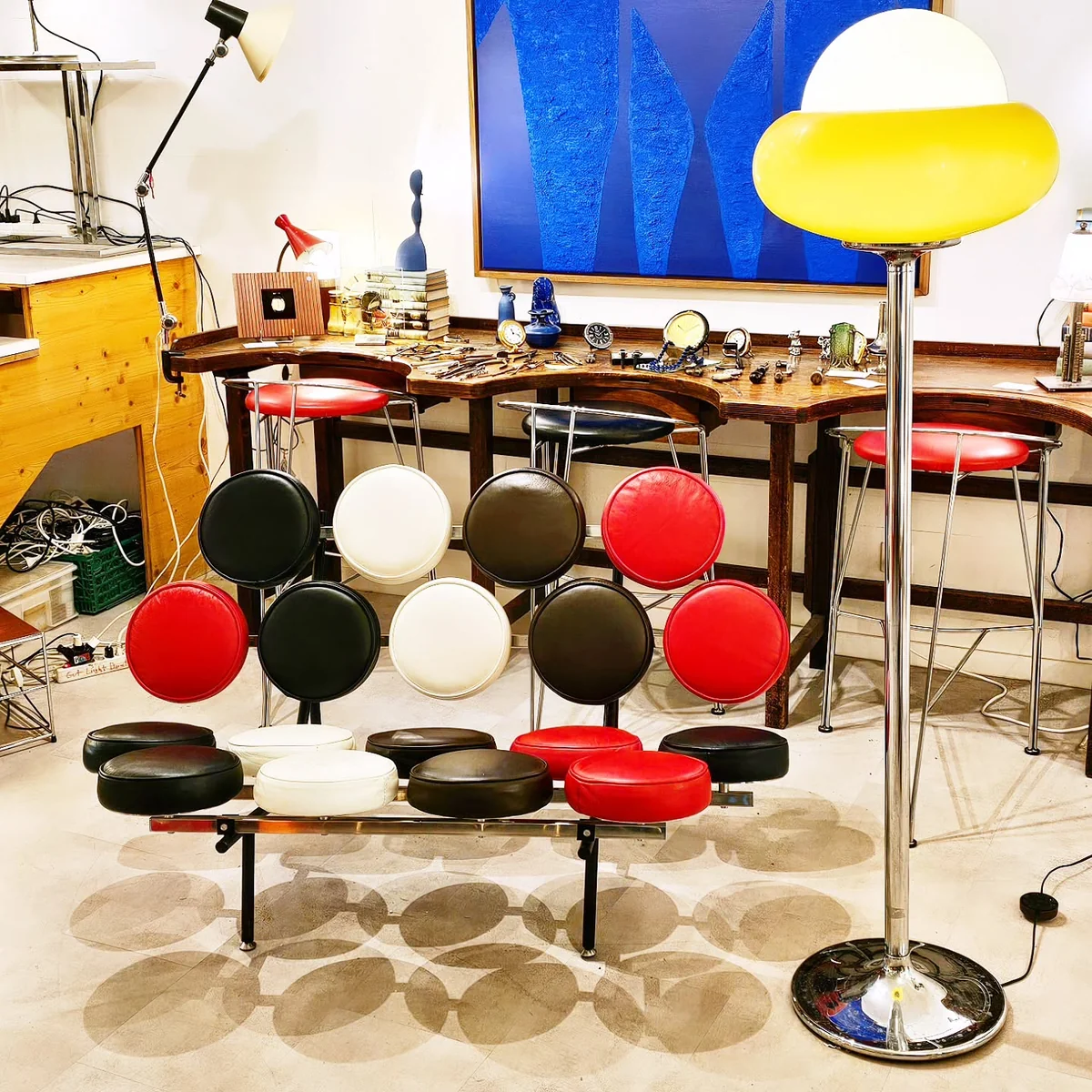Showroom Cyclup Design avec mobilier coloré, une lampe design et un grand tableau bleu.