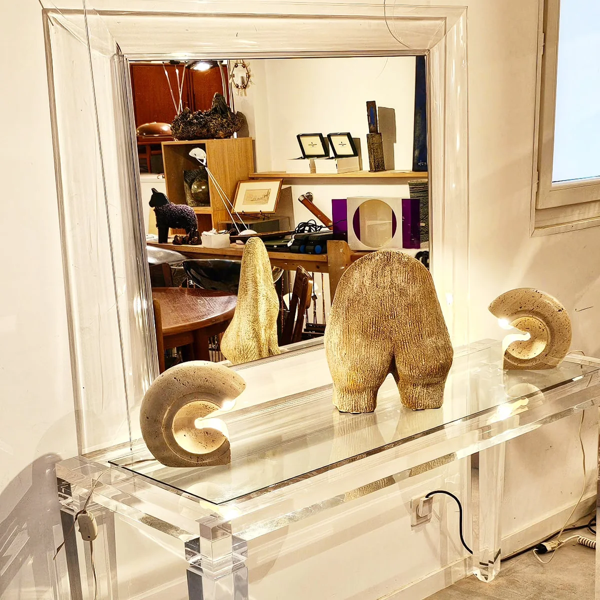 Console transparente avec trois lampes design en forme de spirales et de formes abstraites.