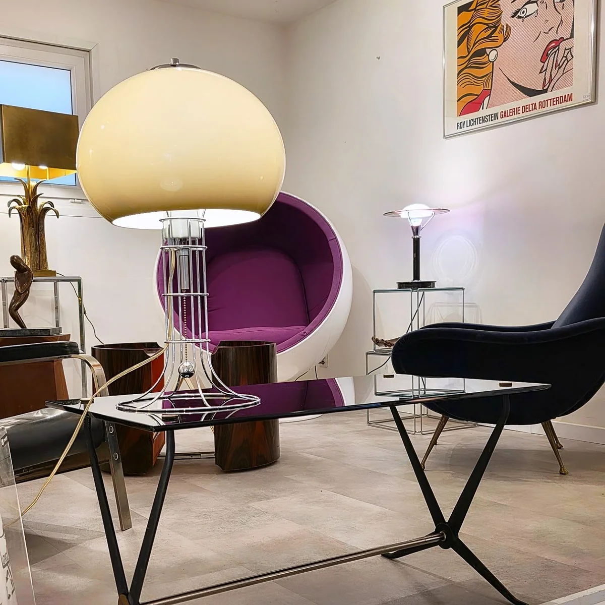 Showroom de mobilier vintage avec des lampes, un fauteuil futuriste et des affiches d'art.