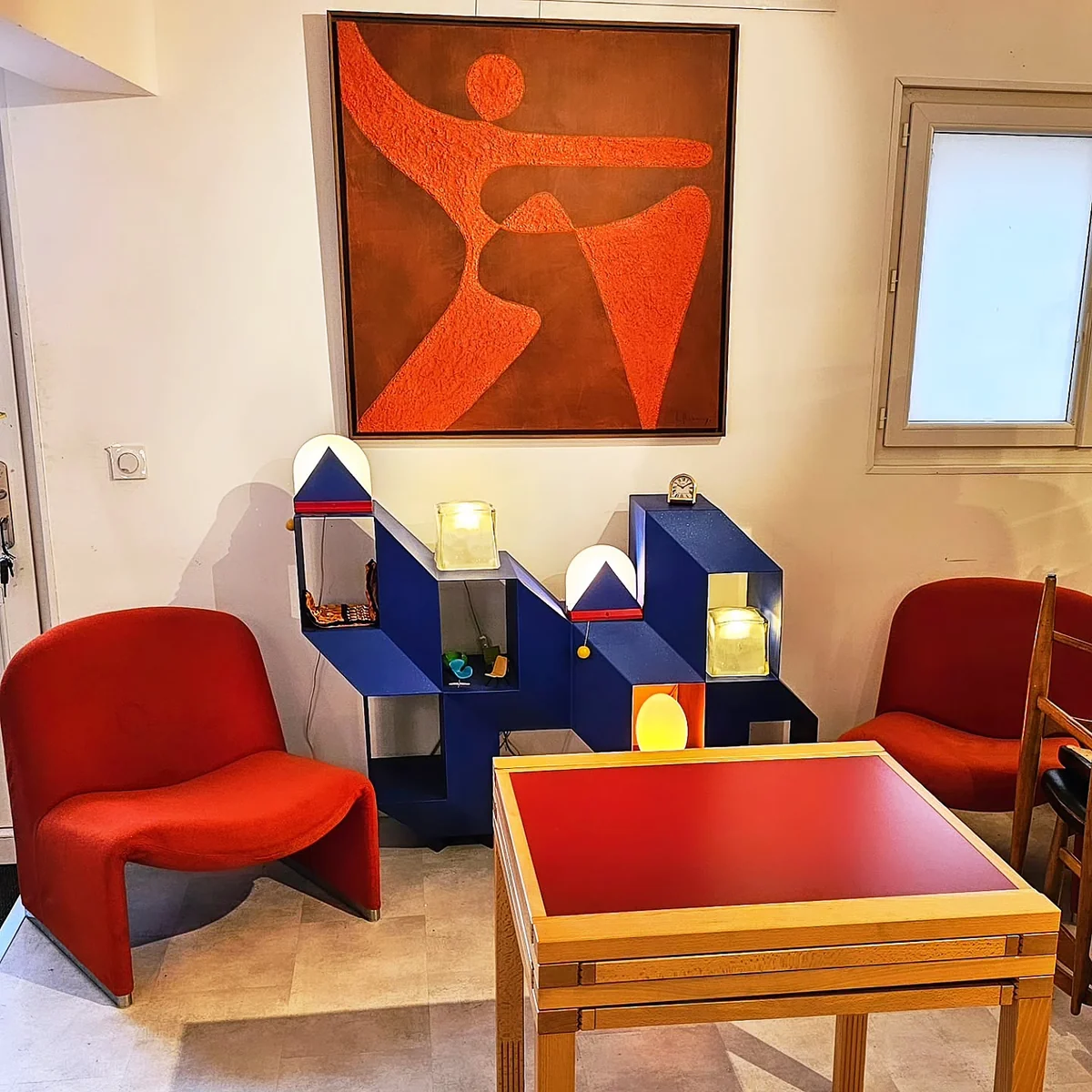 Composition de mobilier vintage rouge et bleu avec un tableau abstrait.